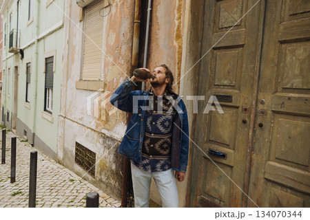 Candid shot of individual strolling city street with coffee Candid shot of individual strolling city street with coffee 134070344