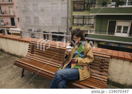 Closeup shot of person observing mobile device on park bench Closeup shot of person observing mobile device on park bench 134070347