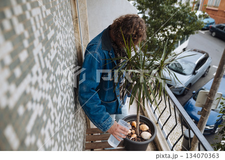 Man caring for plant with pastries in cozy balcony setting 134070363