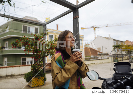 Evening setting with woman savoring beverage near motorcycle 134070413