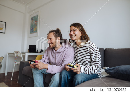Pair of friends sharing leisure time through casual gaming at home Pair of friends sharing leisure time through casual gaming at home 134070421