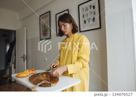Cozy kitchen scene featuring woman dressing pancake with chocolate 134070527