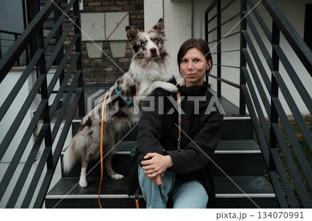 A Border Collie places its paw on the woman s shoulder as they sit on the steps. Concept conveys affection, trust, and emotional bonding between pet and owner 134070991