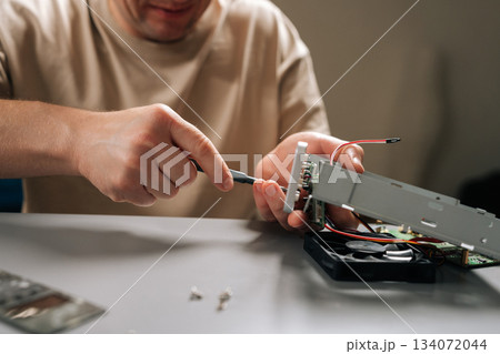 Close-up of man focusing on repairing internal computer hardware components with screwdriver, demonstrating expertise in electronics maintenance and technical servicing. Concept of technical support. 134072044