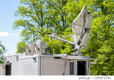 Many modern white mobile digital electric tv broadcasting trucks satellite antenna live streaming online breaking news sport channel city park. Internet communication media vehicle network equipment 134072542