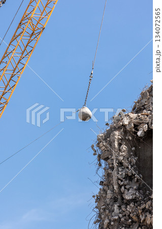 Heavy wrecking ball crane demolishing old building against blue sky in Magdeburg Germany. Building dismantling and construction waste disposal recycling service Heavy wrecking ball crane demolishing old building against blue sky in Magdeburg Germany. Building dismantling and construction waste disposal recycling service 134072565