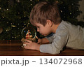 A boy looking at a glass ball with a scene of the birth of Jesus Christ 134072968