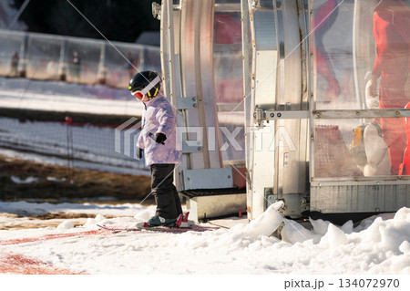 A girl on skis stands on a carpet ski lift in a glass tunel A girl on skis stands on a carpet ski lift in a glass tunel 134072970