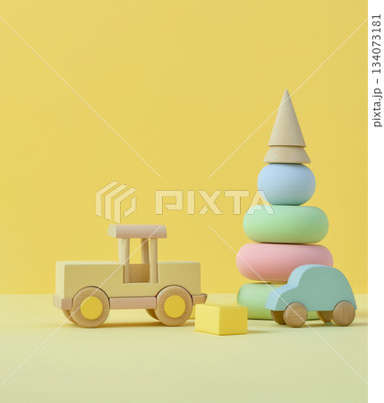 Pastel Wooden Baby Toys with Yellow Background, collection pastel-colored wooden baby toys including stacking tower and toy truck, yellow background to represent early development Pastel Wooden Baby Toys with Yellow Background, collection pastel-colored wooden baby toys including stacking tower and toy truck, yellow background to represent early development 134073181