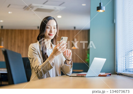 オフィスでスマホを操作するビジネスウーマン オフィスでスマホを操作するビジネスウーマン 134073673