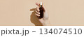 A womans hand holding a brown bottle of serum on a beige background. Body care  134074510