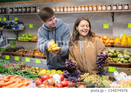 Young couple buying bananas and pomegranates in grocery store Young couple buying bananas and pomegranates in grocery store 134074976