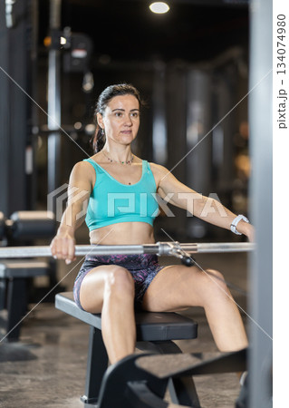 In gym, woman uses cable row machine to strengthen arm muscles In gym, woman uses cable row machine to strengthen arm muscles 134074980