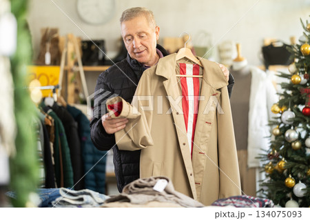 elderly man chooses a trench coat 134075093