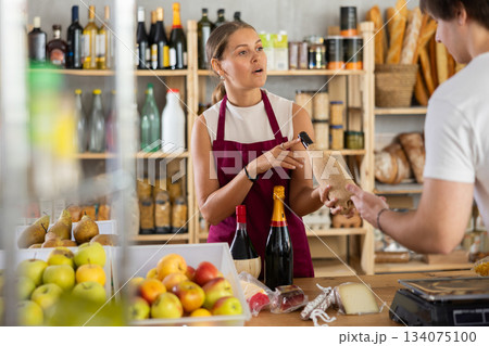 Friendly female salesperson offers to buy bottle of wine to male customer at grocery store Friendly female salesperson offers to buy bottle of wine to male customer at grocery store 134075100