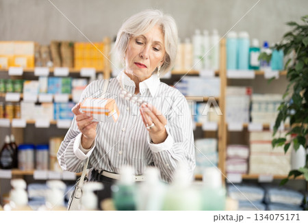 Mature woman choosing paracetamol at the pharmacy Mature woman choosing paracetamol at the pharmacy 134075171