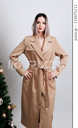Woman in a nude silk pajama set posing elegantly with a hand near her neck 134075211