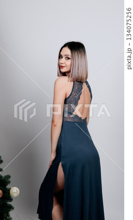 Woman in a dark blue chemise or nightgown posing elegantly in a studio Woman in a dark blue chemise or nightgown posing elegantly in a studio 134075256