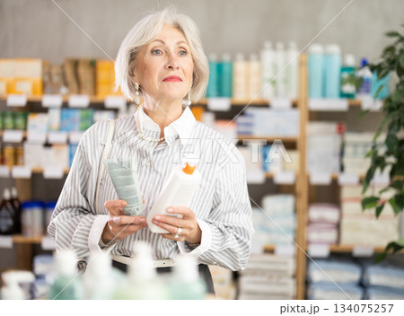 Elderly woman chooses cream at pharmacy Elderly woman chooses cream at pharmacy 134075257