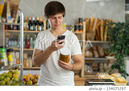 Young man scans a jar of olives on his phone 134075297