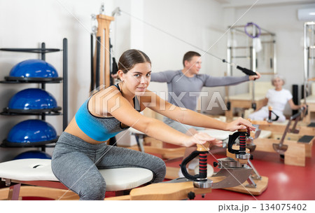 Young woman stretching her arms using pilates machine Young woman stretching her arms using pilates machine 134075402