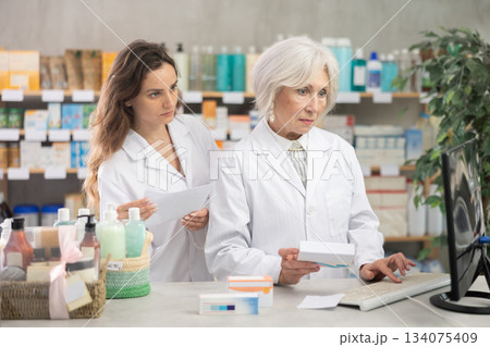 Two female pharmacists employee using computer 134075409