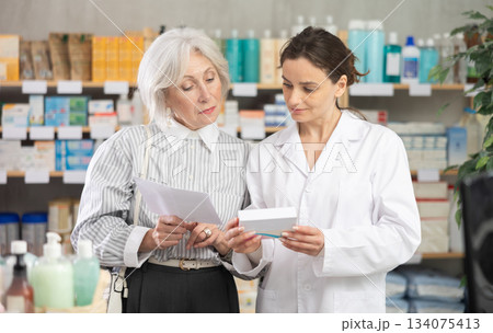 Mature woman consults pharmacist in pharmacy 134075413