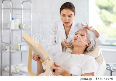 Cosmetologist with gloves preparing patient to skin care procedure in spa salon. 134075576