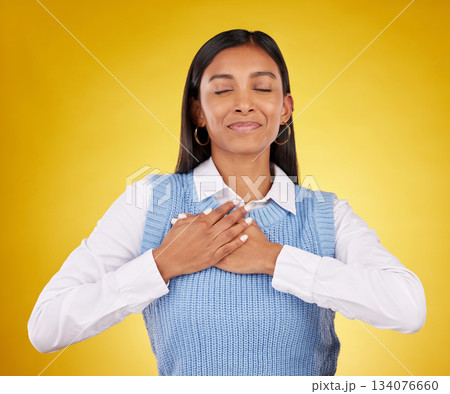 Gratitude, peace and young female in a studio with her hand on her chest for a grateful expression. Mindfulness, smile and Indian woman model with thankful gesture isolated by yellow background. Gratitude, peace and young female in a studio with her hand on her chest for a grateful expression. Mindfulness, smile and Indian woman model with thankful gesture isolated by yellow background. 134076660