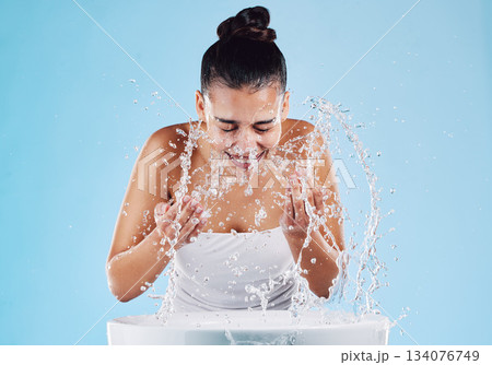 Sink, water splash and skincare of a woman washing face for natural beauty and facial wellness. Isolated, blue background and studio with a female model doing dermatology and cosmetic routine Sink, water splash and skincare of a woman washing face for natural beauty and facial wellness. Isolated, blue background and studio with a female model doing dermatology and cosmetic routine 134076749