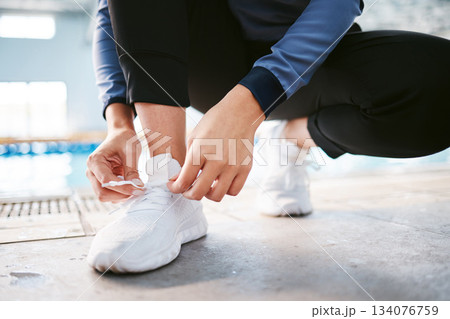 Tie shoes, hands and fitness at swimming pool to start workout, exercise or training. Sports, athlete and woman tying sneakers to get ready for swim, practice or exercising for health and wellness. 134076759