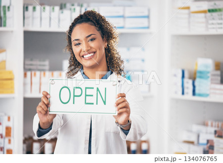 Open, business sign and woman portrait in a pharmacy with billboard from medical work. Working, pharmacist and healthcare worker with a smile from retail store opening and small business poster Open, business sign and woman portrait in a pharmacy with billboard from medical work. Working, pharmacist and healthcare worker with a smile from retail store opening and small business poster 134076765