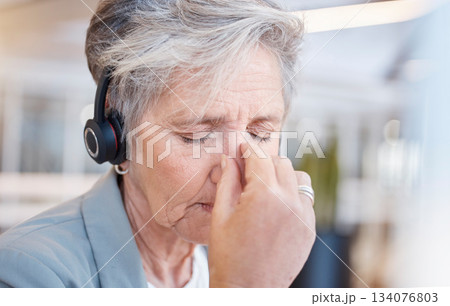 Senior woman, headache and tired at call center with stress from consulting, telemarketing or crm job. Elderly female, tech support consultant and exhausted in office with burnout, fatigue or anxiety 134076803
