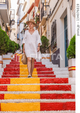 Young woman in a white dress walking down the colourful Spanish Steps in the Arrabal old town district of Calpe, Spain Young woman in a white dress walking down the colourful Spanish Steps in the Arrabal old town district of Calpe, Spain 134076819