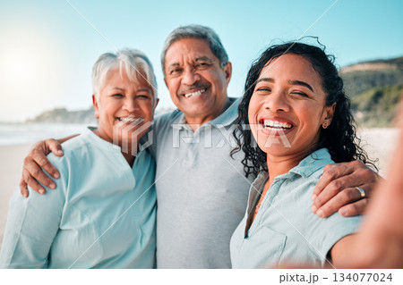 Senior parents, daughter and beach selfie with smile, hug and happiness in summer sunshine for social media. Women, man and portrait with happy, excited face and profile picture with love on holiday Senior parents, daughter and beach selfie with smile, hug and happiness in summer sunshine for social media. Women, man and portrait with happy, excited face and profile picture with love on holiday 134077024