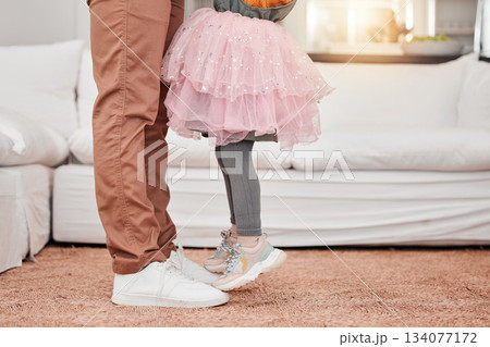 Feet of father and child dancing in the living room of their modern family home to music or radio. Dance, energy and closeup of man bonding, having fun and standing with his daughter in their house. Feet of father and child dancing in the living room of their modern family home to music or radio. Dance, energy and closeup of man bonding, having fun and standing with his daughter in their house. 134077172