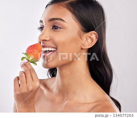 Happy, healthy and a woman eating a strawberry for nutrition isolated on a white background in a studio. Smile, thinking and an Indian girl with a fruit for a diet, breakfast or vitamins from food Happy, healthy and a woman eating a strawberry for nutrition isolated on a white background in a studio. Smile, thinking and an Indian girl with a fruit for a diet, breakfast or vitamins from food 134077203