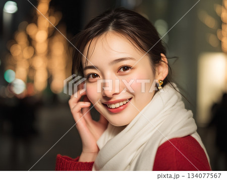 クリスマス、スマホを手にイルミネーションの前で笑顔の女性 134077567