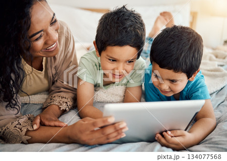 Tablet, education and a mother with her children on a bed at home in the morning together for entertainment. Family, boy or brother with a woman and her kids learning online in the bedroom of a house 134077568
