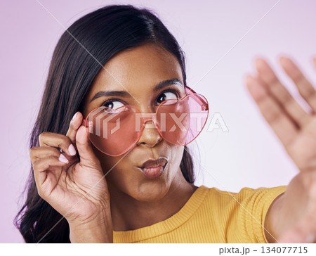 Selfie, heart and sunglasses by indian woman in studio emoji, cool and fun on purple background. Glasses, trendy and female gen z fashion influencer posing for profile picture, photo or blog post 134077715