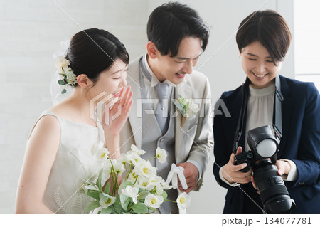 カメラマンが撮影した写真を確認する新婦と新郎　ウエディングイメージ 134077781