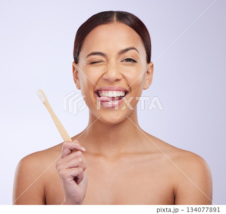 Portrait, wink or happy girl brushing teeth with smile for healthy oral or dental hygiene in studio. Face, beauty or Brazilian woman model cleaning mouth with a natural bamboo wooden toothbrush Portrait, wink or happy girl brushing teeth with smile for healthy oral or dental hygiene in studio. Face, beauty or Brazilian woman model cleaning mouth with a natural bamboo wooden toothbrush 134077891