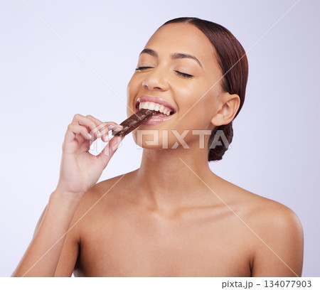 Woman, skincare and studio for eating chocolate with self care, diet or beauty with organic benefits for glow on face. Girl, model and happy for candy with wellness, health or nutrition by background Woman, skincare and studio for eating chocolate with self care, diet or beauty with organic benefits for glow on face. Girl, model and happy for candy with wellness, health or nutrition by background 134077903