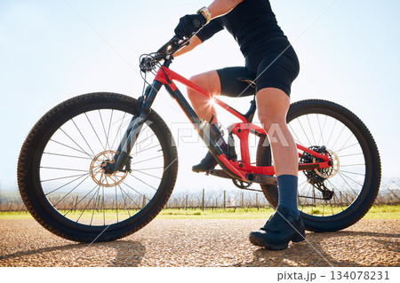 Bicycle, ride outdoor and legs of person on a bike journey for sports race on a gravel road. Fitness, exercise and athlete doing sport training in nature on a countryside trail for cardio and workout 134078231