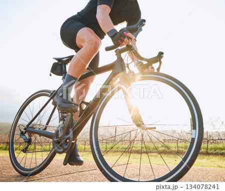 Bicycle, ride outdoor and person on a bike with travel for sports race on a vineyard gravel road. Fitness, exercise and fast athlete doing sport training in nature on a trail for cardio and workout 134078241