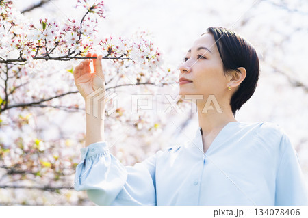 桜の花びらを見る若い女性　ライフスタイルイメージ 134078406