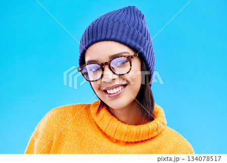 Portrait of woman in winter fashion with smile, beanie and glasses isolated on blue background. Style, happiness and gen z girl in studio backdrop with happy face and warm clothing for cold weather. Portrait of woman in winter fashion with smile, beanie and glasses isolated on blue background. Style, happiness and gen z girl in studio backdrop with happy face and warm clothing for cold weather. 134078517