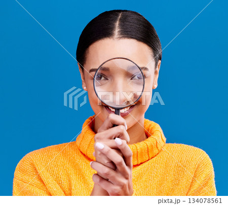 Woman, magnifying glass and smile in studio portrait with funny face, search and zoom by blue background. Gen z girl, investigation and research with lens for study, inspection and check by backdrop Woman, magnifying glass and smile in studio portrait with funny face, search and zoom by blue background. Gen z girl, investigation and research with lens for study, inspection and check by backdrop 134078561