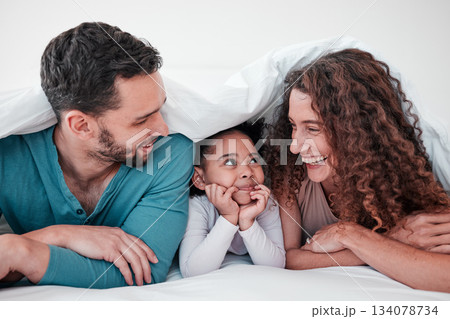 Family, parents are happy with child in bed and relax under blanket in bedroom with smile, love and care. Spending time together, bonding and happiness, man and woman with young girl at home Family, parents are happy with child in bed and relax under blanket in bedroom with smile, love and care. Spending time together, bonding and happiness, man and woman with young girl at home 134078734