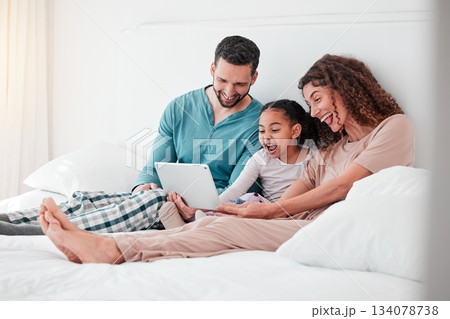 Mom, dad and child on bed with tablet, watching movies, streaming service for child development. Interracial family in bedroom bonding with happy online movie, man and woman with girl and happiness. Mom, dad and child on bed with tablet, watching movies, streaming service for child development. Interracial family in bedroom bonding with happy online movie, man and woman with girl and happiness. 134078738